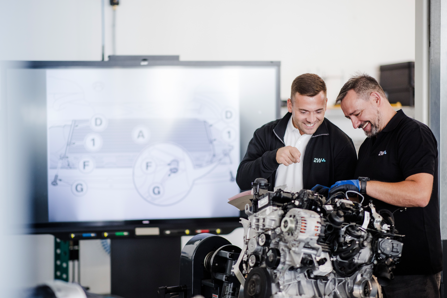 2W Mitarbeiter bei einer Motoranalyse Teamarbeit in der Werkstatt, 2W Mitarbeiter analysieren Motor mit technischer Unterstützung