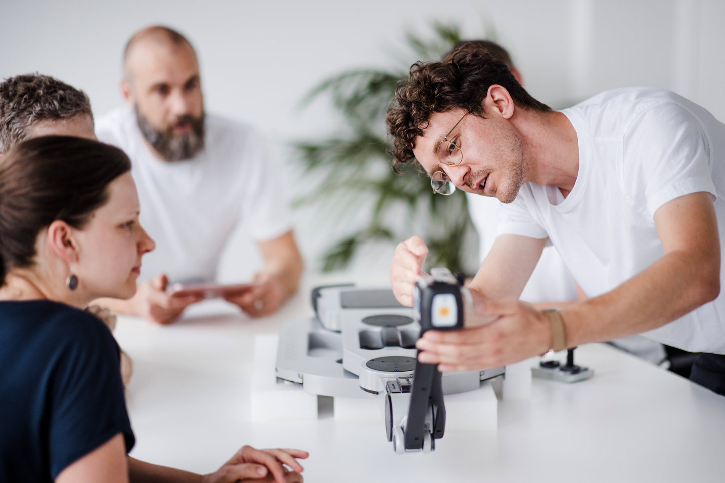 Präzise Analyse von technischen Komponenten Ein Mann zeigt einer Gruppe von Kollegen die Details einer technischen Komponente. Die Gruppe ist konzentriert und aufmerksam, während der Mann die Funktion und Struktur des Bauteils erklärt.